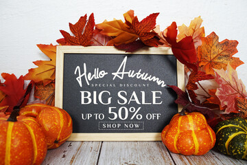 Hello Autumn Big Sale 50% text with maple leaf decoration on wooden background