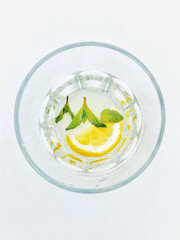 Top view of a glass of refreshing lemonade with lemon slice and fresh mint leaves on a white background