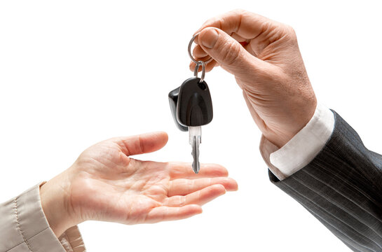 Fototapeta Hand of man in a formal suit handing over car keys to a woman's hand on isolated background. Concept of selling or renting a car