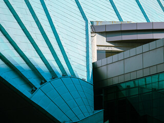 Abstract close-up of modern architectural structure with teal metal panels and sharp geometric lines, showcasing futuristic urban design and construction elements.