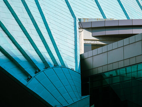 Abstract close-up of modern architectural structure with teal metal panels and sharp geometric lines, showcasing futuristic urban design and construction elements.