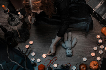 Witch wizard woman witchcrafting, performing ritual with handmade voodoo doll, sitting on the floor...