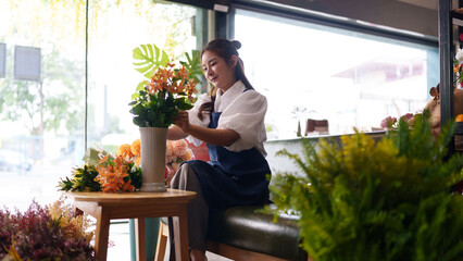 Asian adult florist woman arranging artificial flowers craft retail shop creating beautiful lasting...