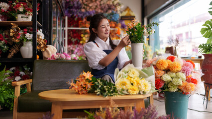 Asian adult florist entrepreneur arranging vibrant artificial flowers for shop display small business success in blooming creative flower boutique studio