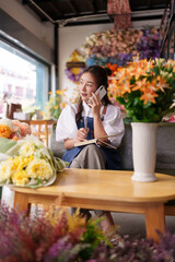 Asian Florist Entrepreneur Manages Orders Takes Calls Operates Small Business In Creative Floral Design Studio Vibrant Flower Shop Environment