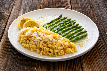 Risotto alla Milanese with green asparagus on wooden table. Milanese style risotto - saffron...