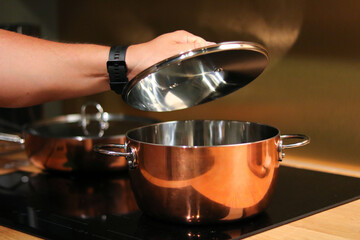 Lifting the Lid of a Copper Cooking Pot in a Modern Kitchen