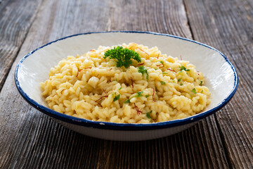 Risotto alla Milanese on wooden table. Milanese style risotto - saffron risotto on wooden background	