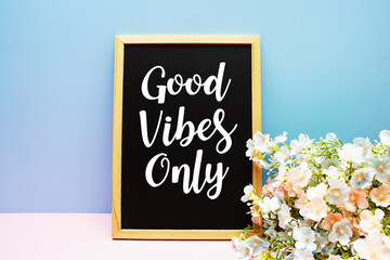 Good vibes only text message with flower decoration on blue background