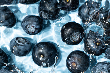 Berry background of fresh whole blueberries in water, splash of water, top view