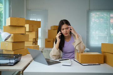 Stressed asian entrepreneur managing online business from home office receiving bad news on phone