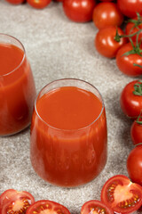 Fresh Tomato Juice in Glasses with Ripe Tomatoes Around.