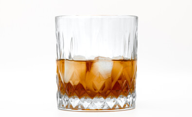 Cold whiskey with ice cubes in a crystal glass, close-up of the glass, white background