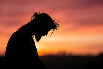 Naklejka premium Silhouette of a figure wearing a crown of thorns against a vivid orange and red sunset. Focus on faith, sacrifice, and reflection.