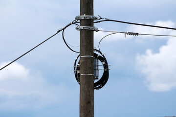 A utility pole with a mounted fiber optic splice enclosure and a coiled drop cable facilitates...