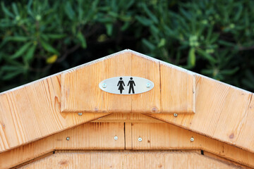 An engraved metal sign displaying male and female pictograms is mounted above the entrance of a...