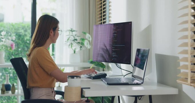 Young adult Asia female freelance eyeglasses typing write prompt AI bot IT app smart program nomad, video game, terminal with coding, user interface, data center on desktop computer at home office.