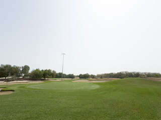 Obraz premium Manicured fairways and palm-lined greens of Abu Dhabi Golf Club on a bright, sunny day, showcasing the serene desert oasis setting