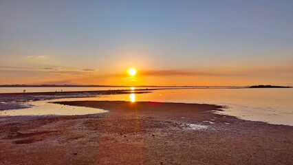 A breathtaking scene unfolds as the sun sets over the tranquil beach