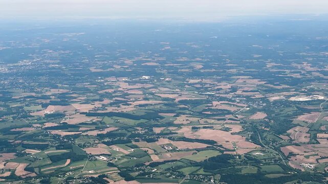 Suburban homes and roads are scattered among dense green forest stretching toward a distant town center. High quality 4k footage