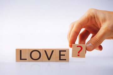 Wooden cubes with the letters LOVE, the hand puts a cube with a red question mark. The concept of...