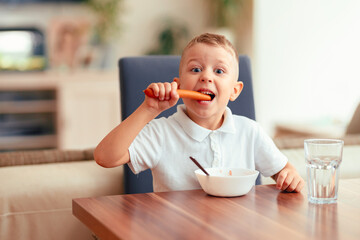 Emotional boy eating sausage at home