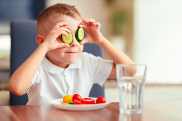 Creative boy playing with vegetables while eating