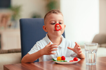 Creative boy playing with vegetables while eating