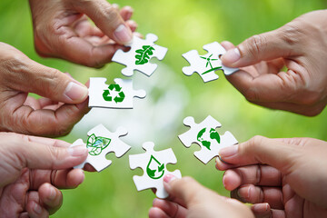 Hands Connecting Eco Puzzle Pieces with Green Symbols Outdoors