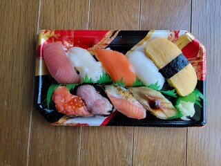 Assorted sushi nigiri presented in a takeaway tray, displaying various fish and egg toppings.