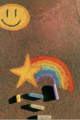 Colorful chalk drawing on pavement with rainbow, star and smiley face