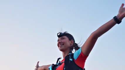 Joyful Caucasian female runner celebrating achievement during cross-country run, wearing headlamp...