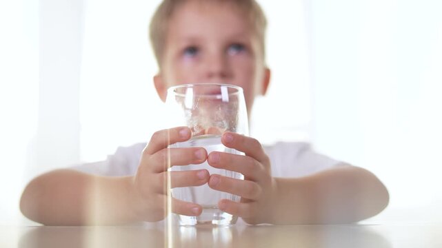 Boy drinks water from a glass in the kitchen. liquid healthy drink beverage concept. a boy drinks water from lifestyle a. glass. the boy drinks water and holds a glass cup.