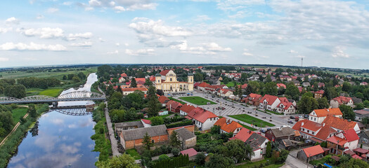 Wide, panoramic, aerial shot of the Narew river, iron bridge, main square and baroque church in picturesque town of Tykocin.  