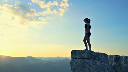 Determined female runner triumphs on rocky peak at sunrise, symbolizing cross-country endurance and...
