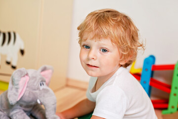 Portrait of a little toddler boy playing in his playroom with toys. Happy child enjoying indoor...