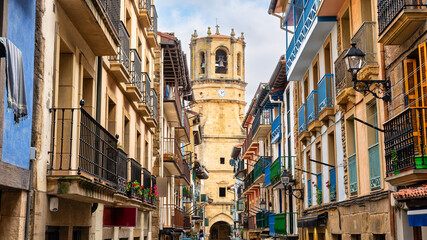 Naklejka premium Main street of the historic center of Getaria with old buildings and the church of San Salvador at the end of the street, Basque Country