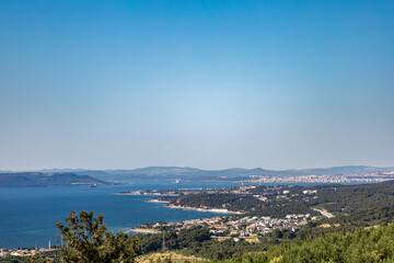 Panoramic view of Çanakkale city, coastline, and Aegean Sea under clear blue sky, seen from a high...
