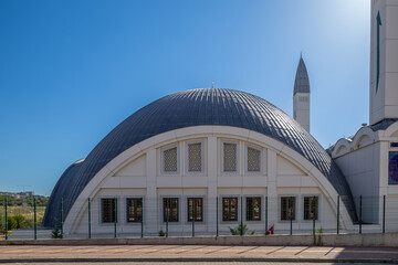 Modern mosque with a semi-circular dome and tall minaret under clear blue sky, Tacettin Aslan Mosque