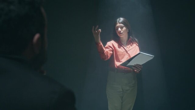 Over the shoulder shot of unrecognizable filming director thrilled by theatrical performance of aspiring actress for her acting audition in dark studio