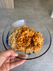 Closeup image of a woman holding a cauliflower and chickpea curry in a glass bowl
