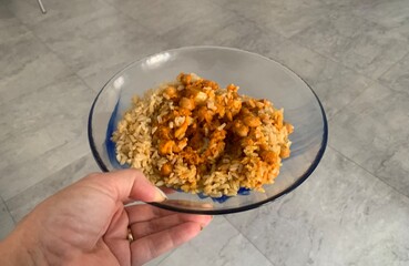Closeup image of a woman holding a cauliflower and chickpea curry in a glass bowl