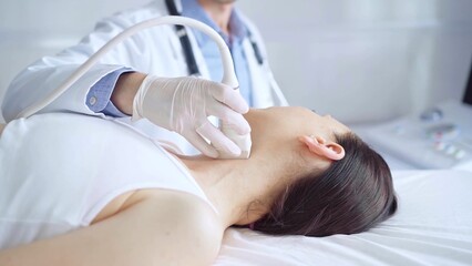 Fototapeta premium Doctor man is using ultrasound equipment on neck of female patient lying down for a medical examination. Medicine and science