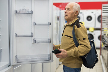 senor man pensioner buying fridge in showroom of electrical appliance store