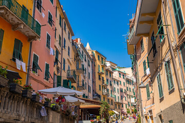 A photo of a narrow street with a few buildings and people walking