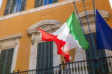 Un drapeau Italien flotte devant une façade Jaune typique d'Italie