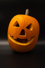 Close-up view of orange Halloween pumpkin with carved face lying on black background. Soft focus....