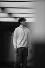 young boy wearing a white blouse and black jeans standing on concrete wall. urban street style