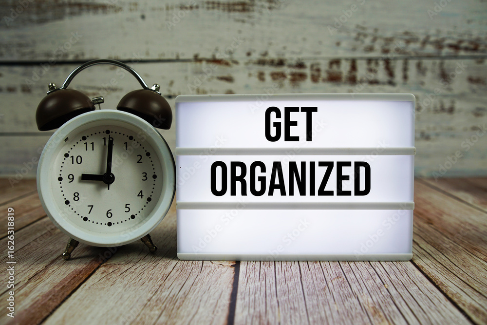 Poster get organized text on light box with alarm clock on wooden background