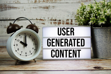 User Generated Content text on light box with alarm clock on wooden background